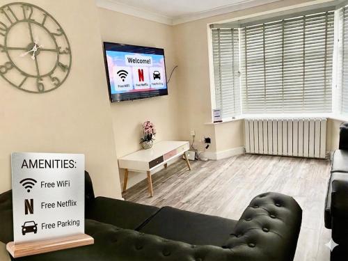 a living room with a couch and a large clock at Modern 4-bedroom entire house with Garden in Uxbridge