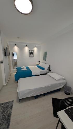 a large white bedroom with two beds and a chandelier at Christina's Studio in Kalabaka