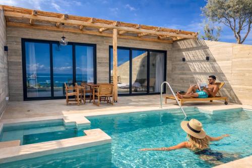 a man and a woman sitting in the swimming pool of a house at Sea view villa with private swimming pool in Heraklio