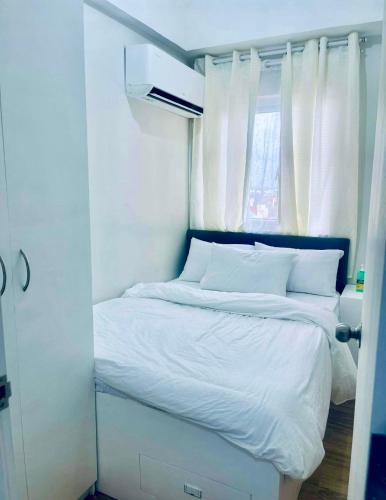 a bedroom with a bed with white sheets and a window at NagaCityRiverView 2BR Apartment in Naga
