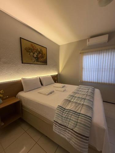 a bedroom with a large white bed with a window at Serra Charm House in Ubajara
