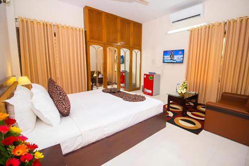 a bedroom with a bed with white sheets and pillows at Hotel Sweet Place in Dhaka