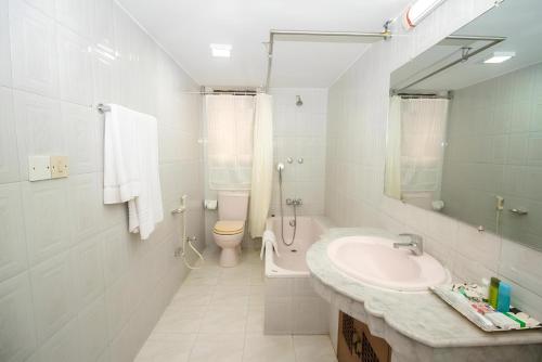a white bathroom with a sink and a toilet at Hotel Sweet Place in Dhaka