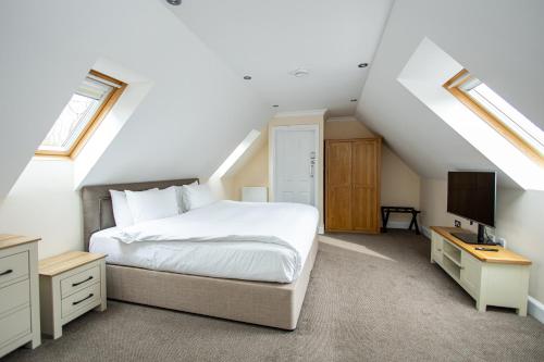 a bedroom with a white bed and a television at Terlingham Lane Cottage in Folkestone