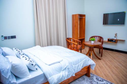 a bedroom with a bed and a table with a television at Uhondo Apartments in Dodoma