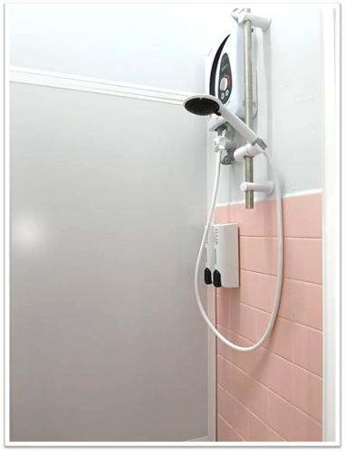 a shower head in a bathroom with a pink wall at Aplus Homestay Kluang A嘉民宿 in Kluang