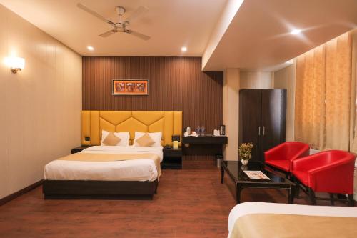 a hotel room with two beds and a red chair at Hotel Krishnam Vrindavan in Vrindāvan