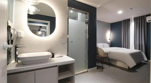 a bathroom with a bed and a sink and a mirror at 아티초크 호텔 in Kajŏng-dong