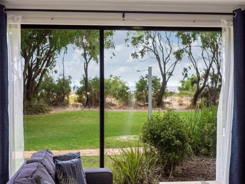 a living room with a sliding glass door looking out at a yard at 1CapeView beachfront Geographe Bay in Broadwater