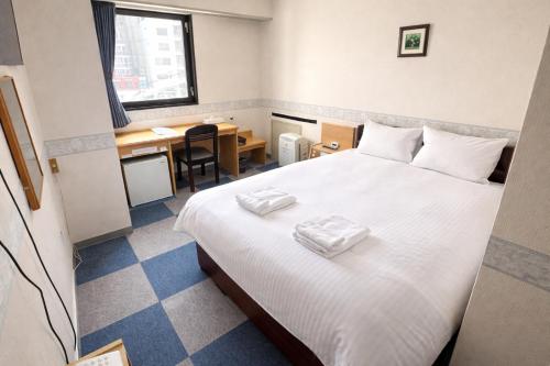 a room with a bed with two towels on it at スマートホテル福島駅前店 in Fukushima
