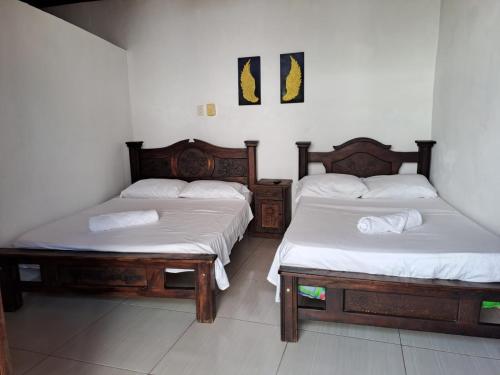 two beds in a room with white sheets at Casa Samuel in Honda