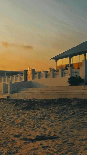 a building on the beach with the sunset in the background at Maan Resort in Mogadishu
