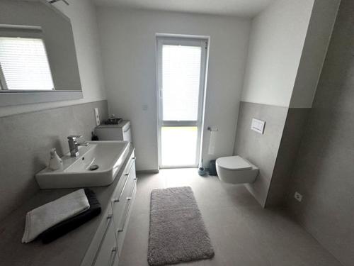 a white bathroom with a sink and a toilet at Moderne Wohnung am Flussufer in Herford