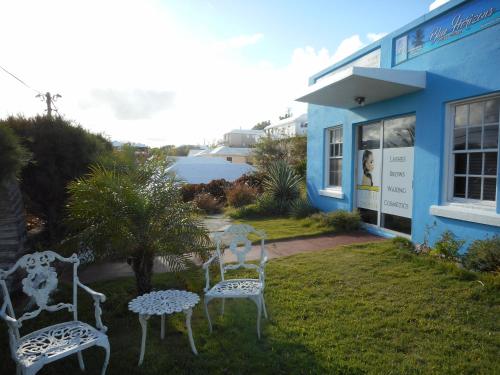 two white chairs sitting in the grass in front of a building at Blue Horizons Guest House in Warwick Camp
