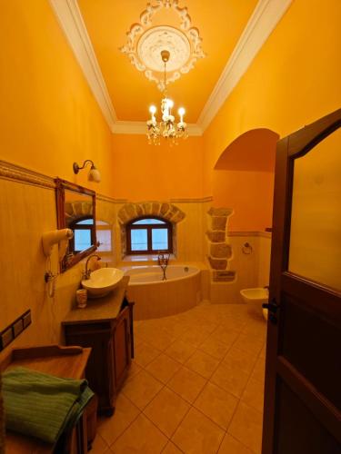 a bathroom with a sink and a tub and a chandelier at Pałac Książęcy we Wleniu in Wleń