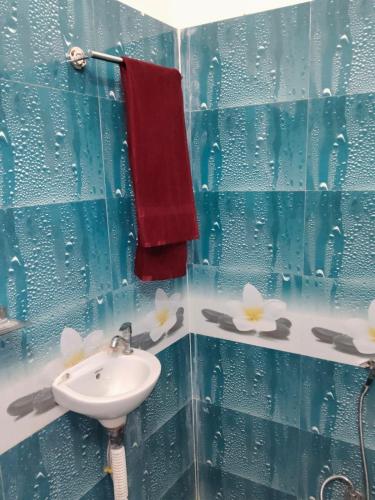 a blue tiled bathroom with a sink and a red towel at Hotel Maa Bhagvati in Orchha