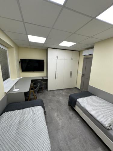 a room with two beds and a desk and a tv at Fully Equipped Guest House Košice-Barca in Košice