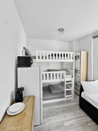 a small room with two bunk beds and a table at London Duo & Quad Rooms in Zone 2 - Willesden Green in London