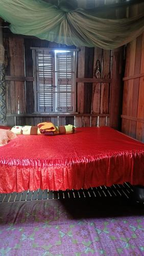 a bedroom with a red bed in a room with wooden walls at Homestay in Kampong Cham in Kampong Cham