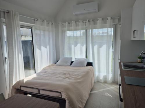 a bedroom with a bed with white sheets and windows at Le cocoon idyllique in Faverolles-sur-Cher