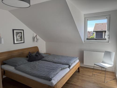 a bed in a room with a window and a chair at Haus Karla in Langeoog