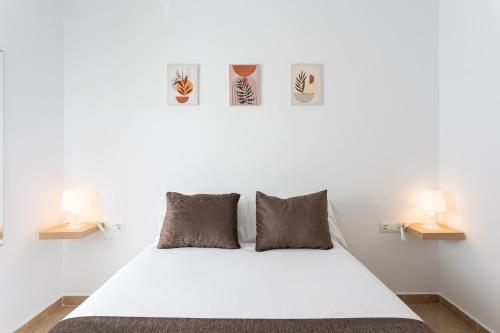a bedroom with a white bed with two lamps at Apartamento Los Angeles Cerca Estación Tren Aeropuerto in Málaga