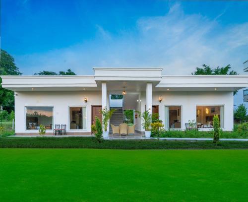 a white house with a green lawn at Corbett The Regnum Resort in Rāmnagar