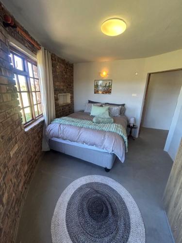 a bedroom with a bed and a brick wall at DaisyRiver Cottage in Port Alfred