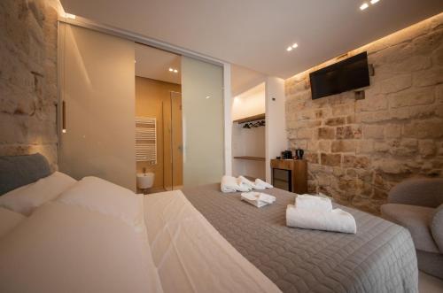 a bedroom with a large bed and a stone wall at Le Quattro Perle in Monopoli