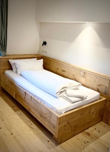 a wooden bed with white sheets on it in a room at Vogelbauer Apartments in Egling