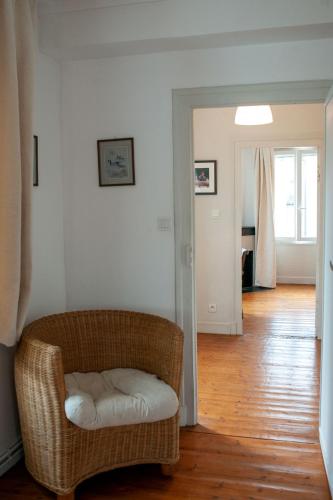 a living room with a wicker chair and a wooden floor at Le Petit Marigny in Marigny-lʼÉglise