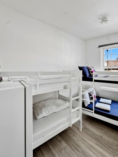 a white room with two bunk beds and a window at Family Rooms for 6 in Zone 2 - Willesden Green in London
