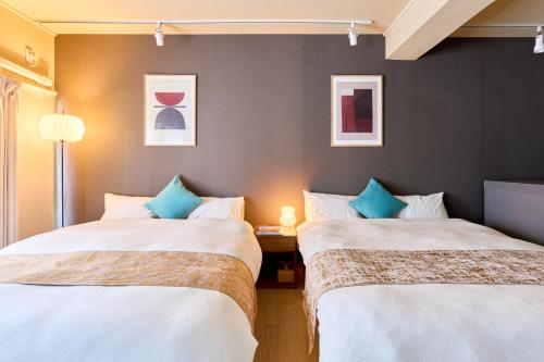 a room with two beds and a table with a lamp at Tokyo Base Meguro in Tokyo
