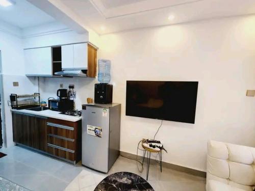 a kitchen with a refrigerator and a tv on the wall at Lanson in Nairobi