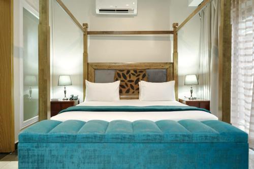 a bedroom with a large bed with a blue ottoman at Lifestyle Boutique Hotel in Lilongwe