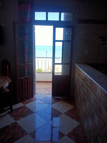 a door to a room with a view of the ocean at Location près de la plage in Tichi