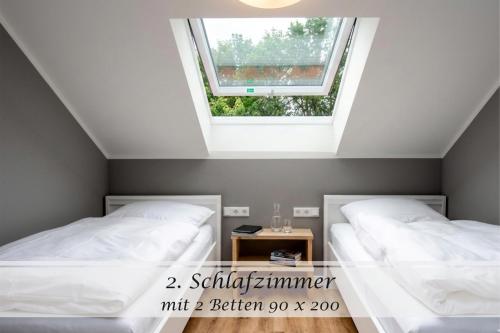two beds in a room with a window at Ferienwohnung Freia - Gulfhof nahe Greetsiel mit Sauna, Garten & 3 Schlafzimmern in Krummhörn