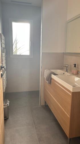 a white bathroom with a sink and a window at Villa Lagune in Les Sables-d'Olonne