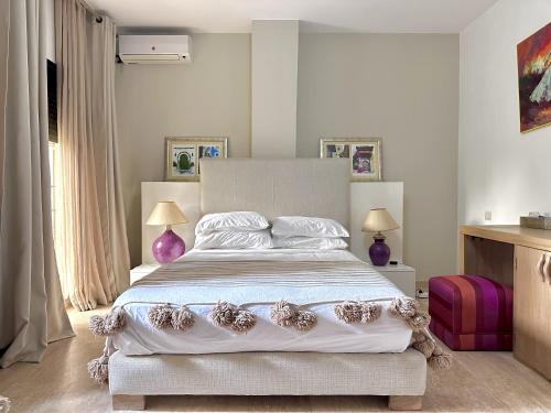 a bedroom with a large white bed with purple accents at Bab louka in Aït Bou Zguia