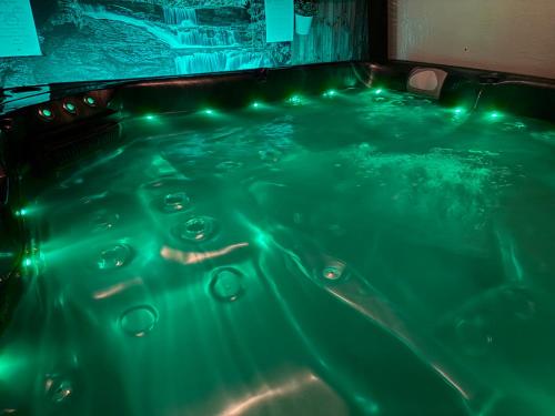 a hot tub with green lights in a room at Acorn Cottage in Ollerton
