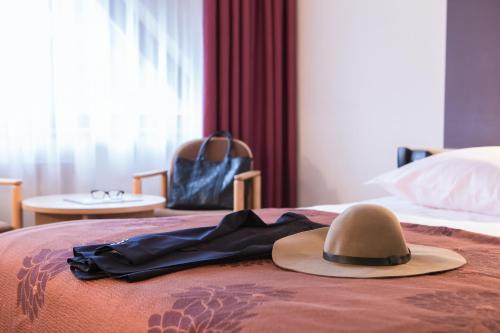 a hat on top of a bed with a robe at Mercure Jelenia Góra in Jelenia Góra