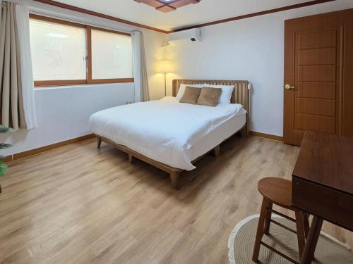a bedroom with a white bed and a wooden floor at Wizday Stay in Suwon