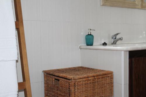 a bathroom with a sink and a basket under a sink at Casas de Miróbriga in Santiago do Cacém