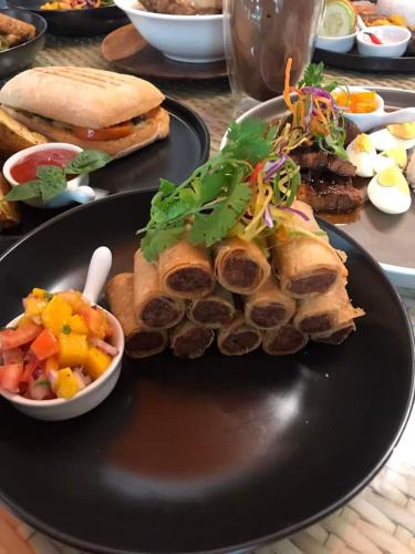 a black plate of food with a sandwich and vegetables at Wanderlust Bed and Breakfast Puerto Princesa in Puerto Princesa City