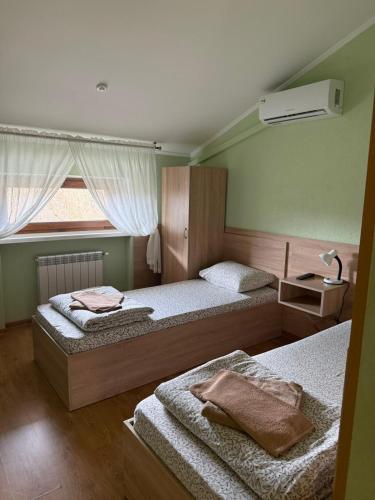 ein Schlafzimmer mit zwei Betten und einem Fenster in der Unterkunft Каприз in Kamjanez-Podilskyj