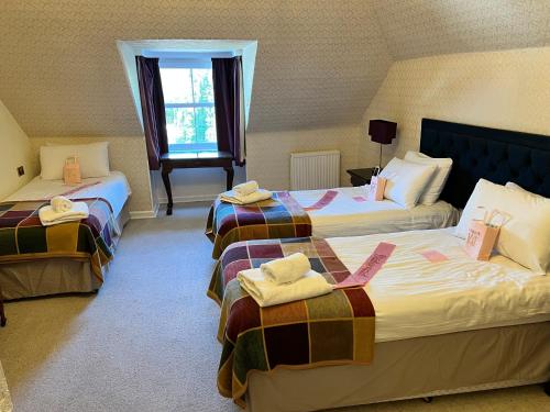 a hotel room with two beds and a window at McArthur Manor in Blairgowrie