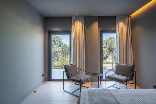two chairs and a table in a room with windows at The Alma Suite in Alora