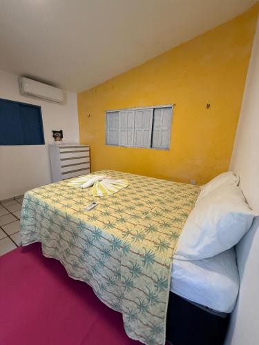 a bedroom with a bed with a yellow wall at Apartamentos e Casas em Barra do Cunhaú in Canguaretama
