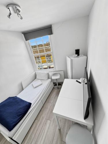 a small white room with a bed and a desk at Room for 5 in Zone 2 - Willesden Green in London