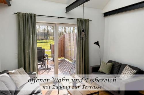 a living room with a couch and a sliding glass door at Ferienwohnung Frieda - Gulfhof nahe Greetsiel mit Sauna, Garten & 3 Schlafzimmern in Krummhörn